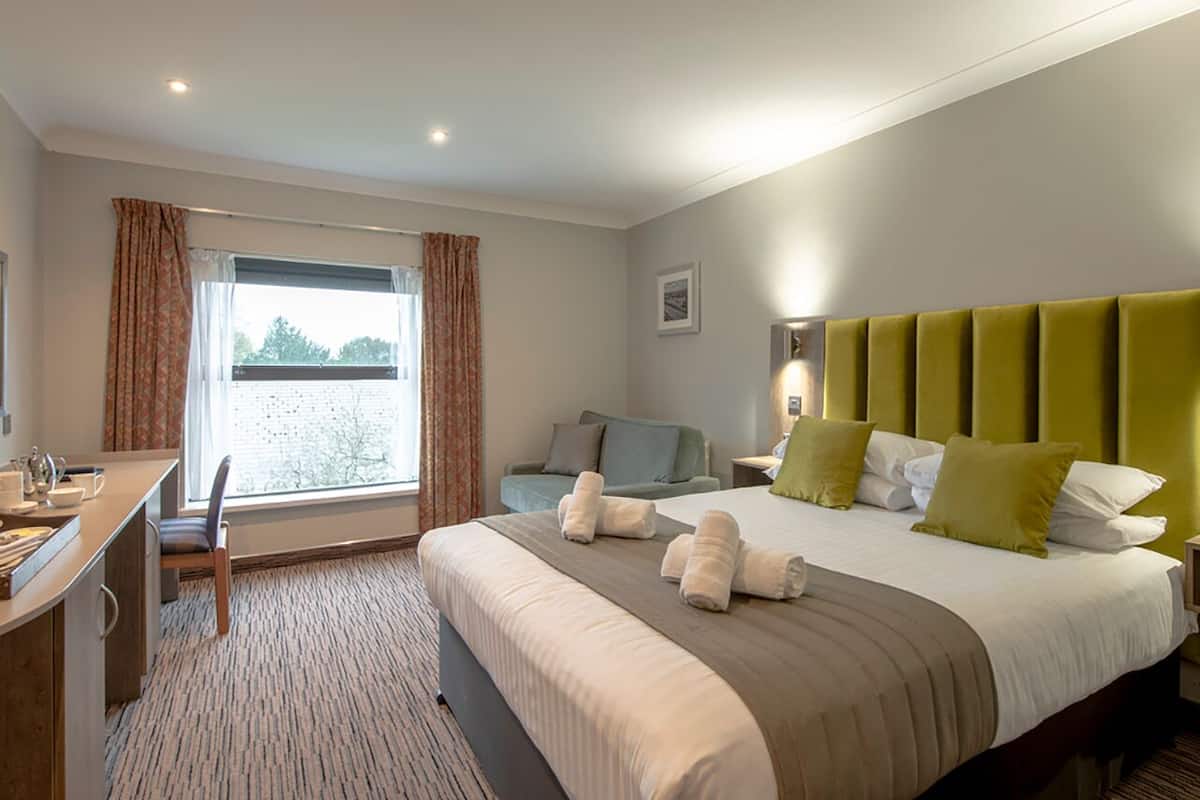 Een hotelkamer met een bed, een bureau, een stoel en een raam met gordijnen.
