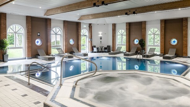 A large indoor swimming pool with multiple lanes, surrounded by lounge areas and large windows. - The Hog's Back Hotel & Spa Farnham (Farnham)