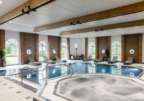 A large indoor swimming pool with multiple lanes, surrounded by lounge areas and large windows. - The Hog's Back Hotel & Spa Farnham (Farnham)
