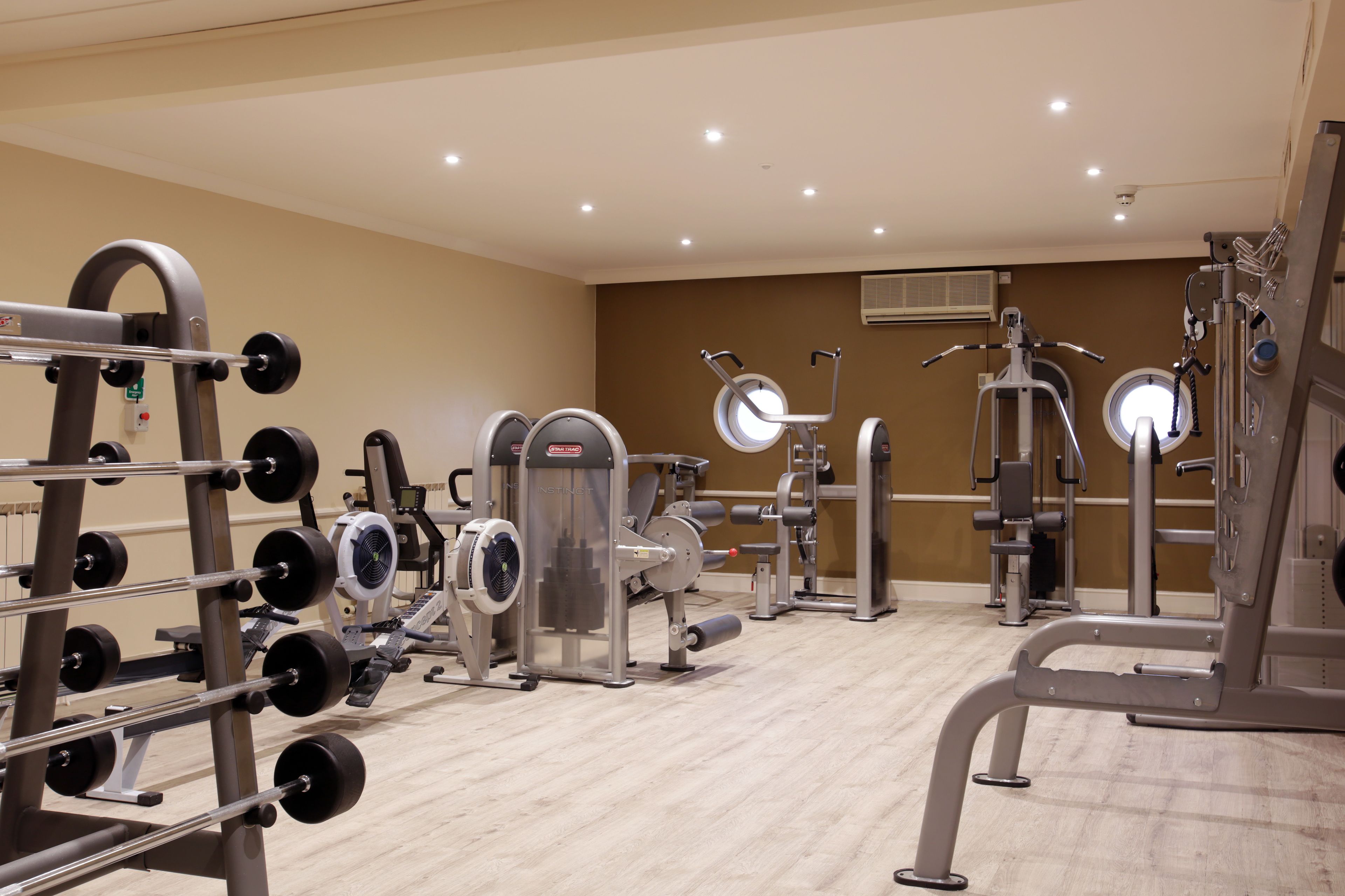 A gym with various exercise equipment, including weight machines, a fan, and a mirror.