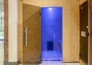 Enter a serene space with a secure door leading to a sauna or steam room featuring a tiled floor and a step.
