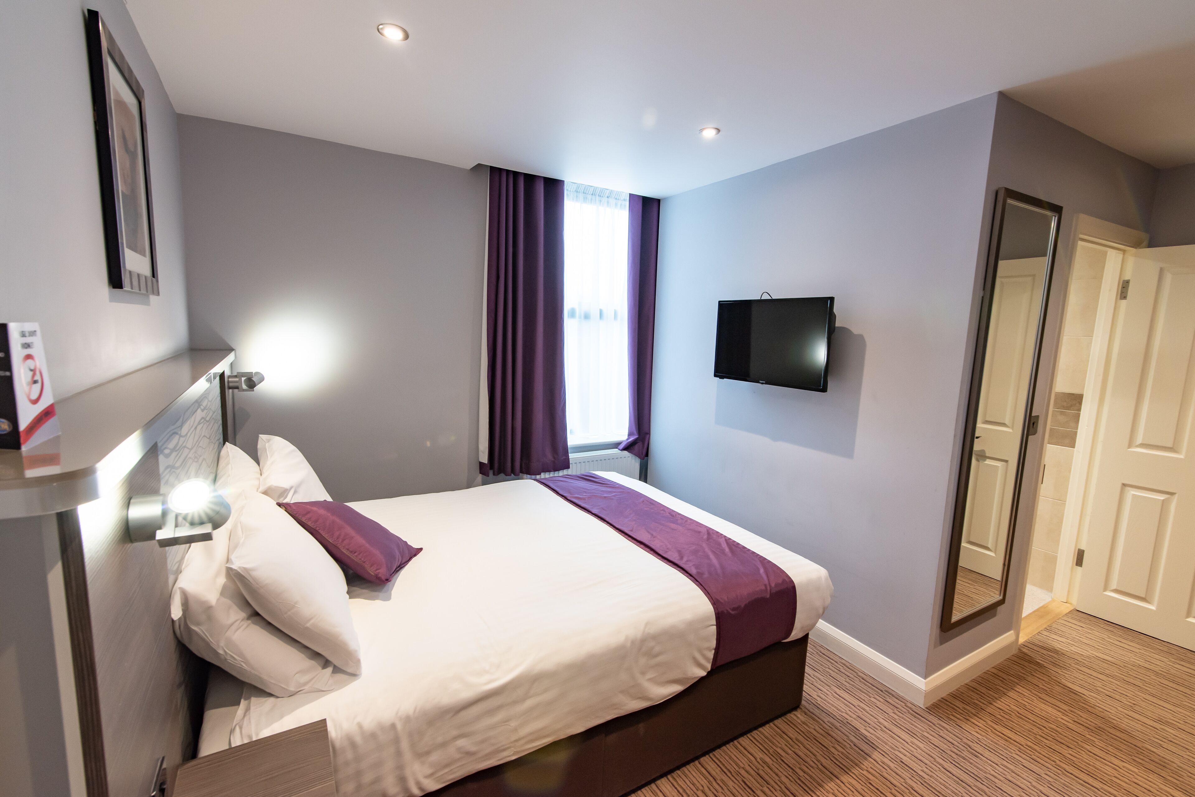 Un hotel modern amb un llit gran, televisió de pantalla plana i un armari encastat.
