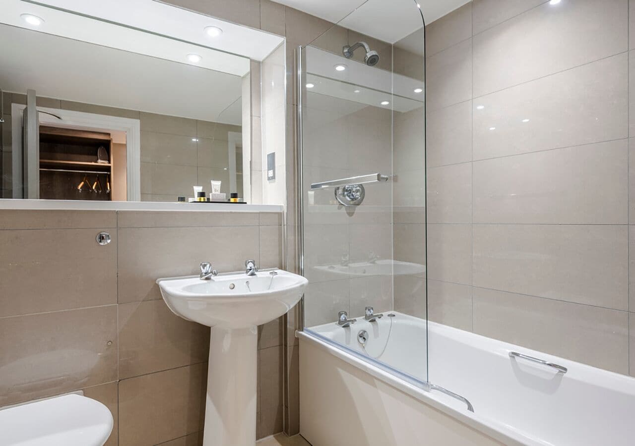A modern bathroom with a glass-enclosed shower, a pedestal sink, and a freestanding bathtub.