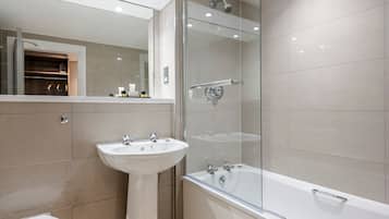 Un baño moderno con ducha envuelta en vidrio, lavamanos pedestal y bañera independiente.