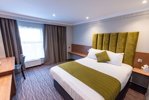 Una habitación de hotel con una cama grande, un escritorio y una silla.