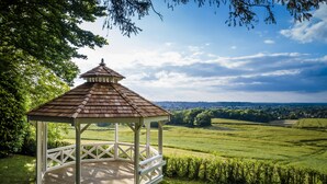 A gazebo with a tiled roof and white railings, surrounded by lush green fields and trees. - The Hog's Back Hotel & Spa Farnham (Farnham)