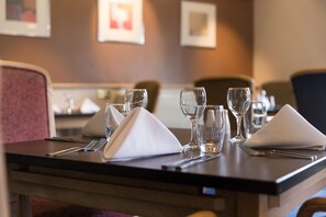 Enjoy a stylish meal in the comfort of your room, with a beautifully set dining table and elegant artwork on the wall.