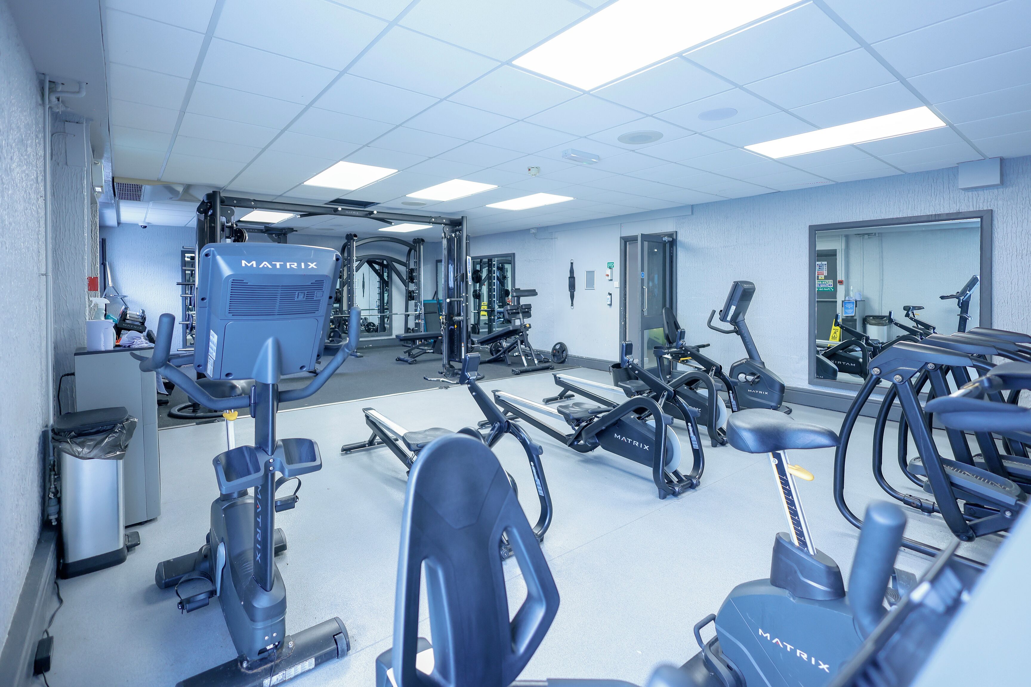 A gym with various exercise equipment, including treadmills and stationary bikes, arranged in a spacious layout.