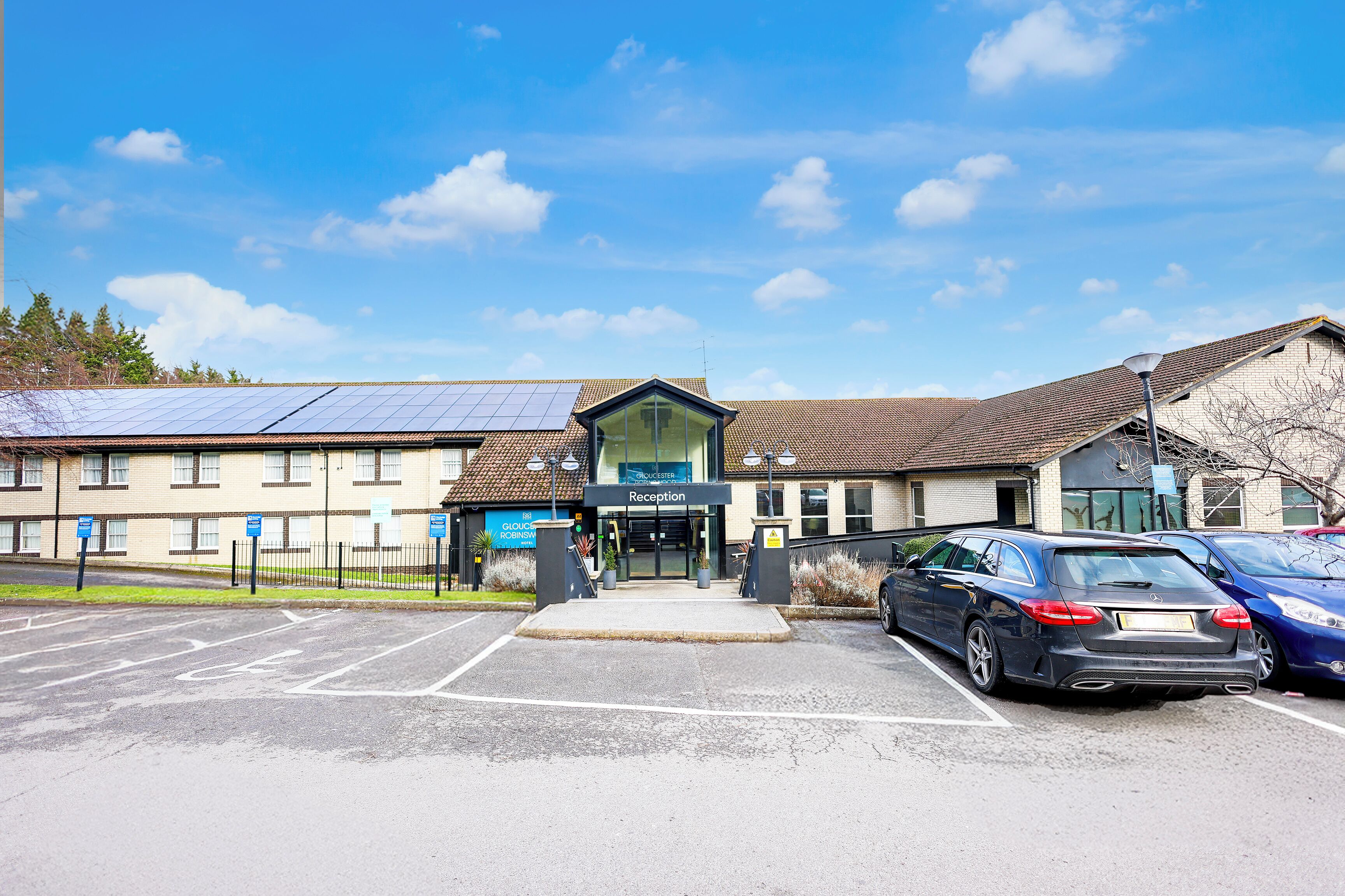 A building with a reception area, parking lot, and solar panels on the roof.