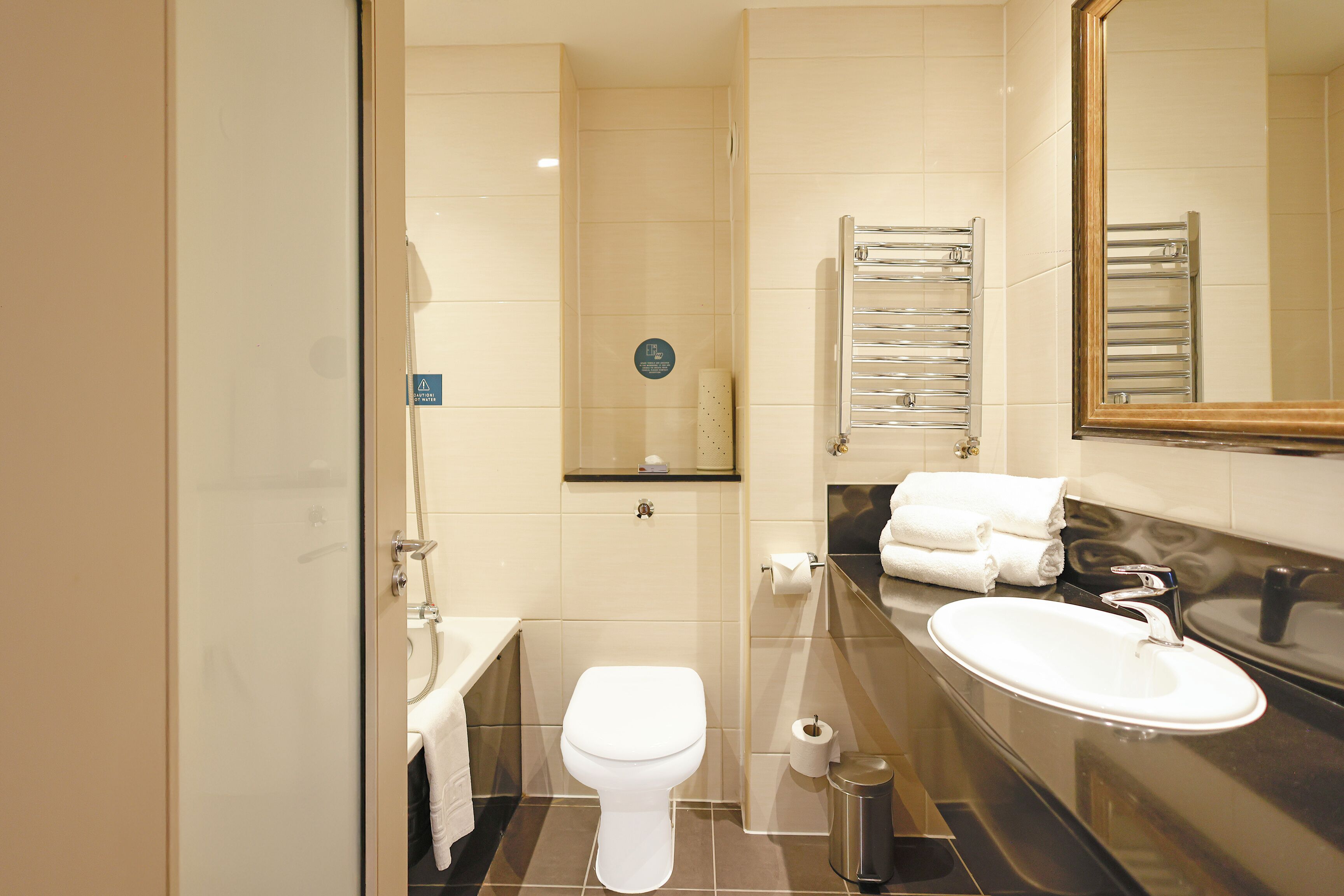 A modern bathroom with a toilet, sink, and towel rack.