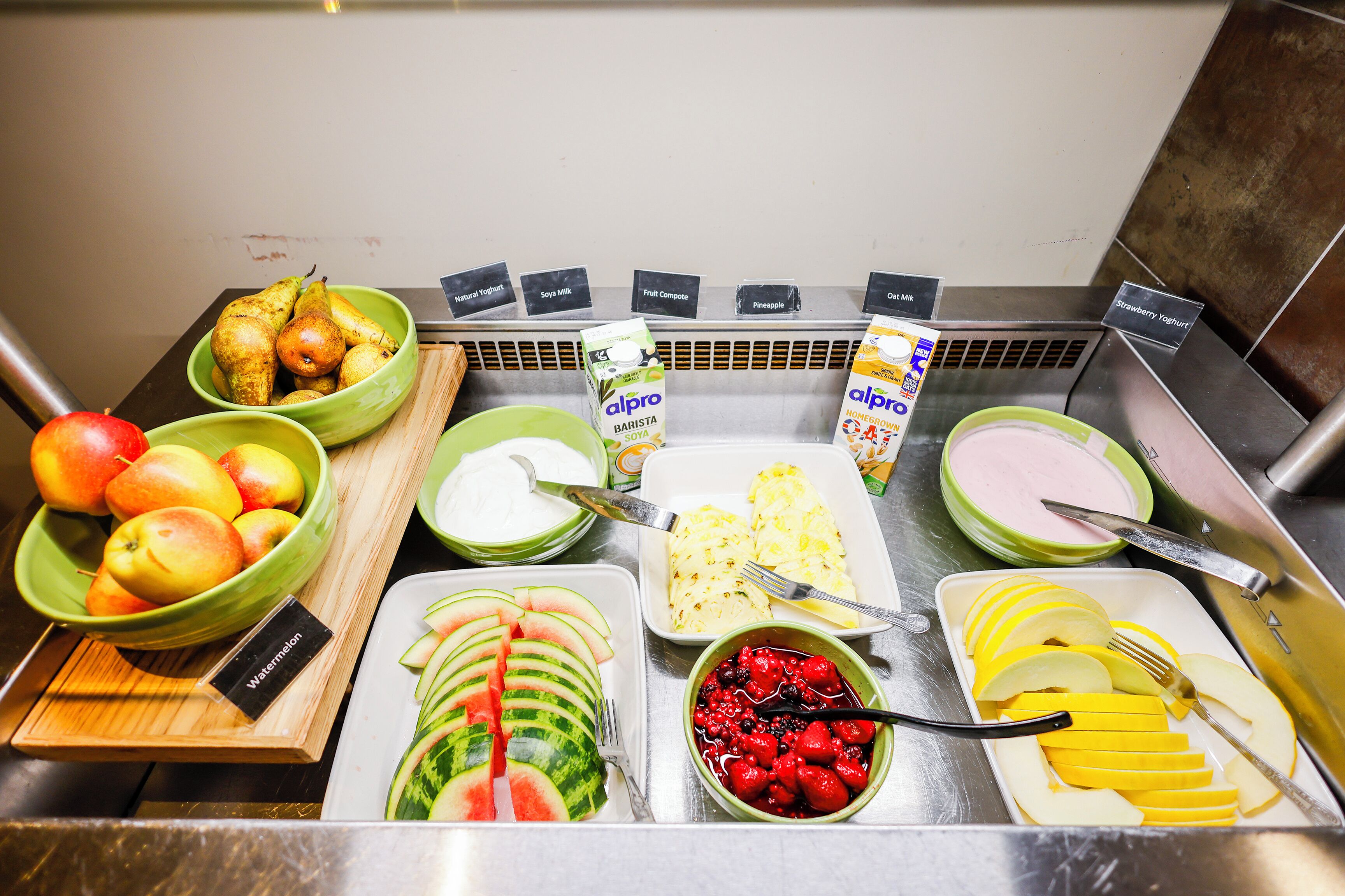 A buffet with various fruits, yogurts, and dairy products.