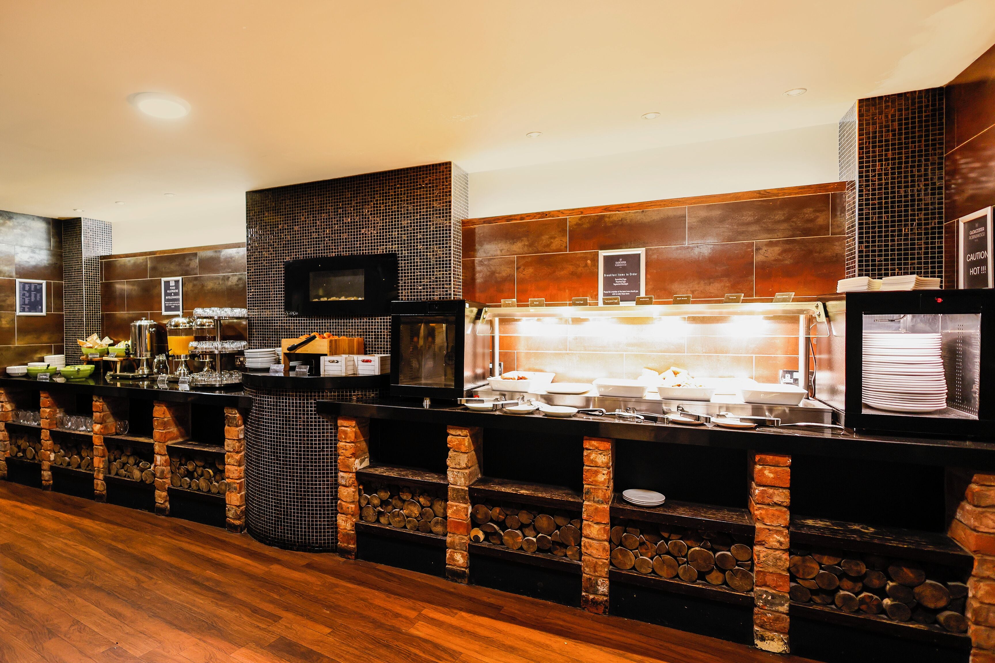 A buffet setup with a variety of food items and beverages, a television, and a tiled backsplash.