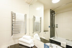 A modern bathroom with a large mirror, two towel racks, a sink, and a shower area.