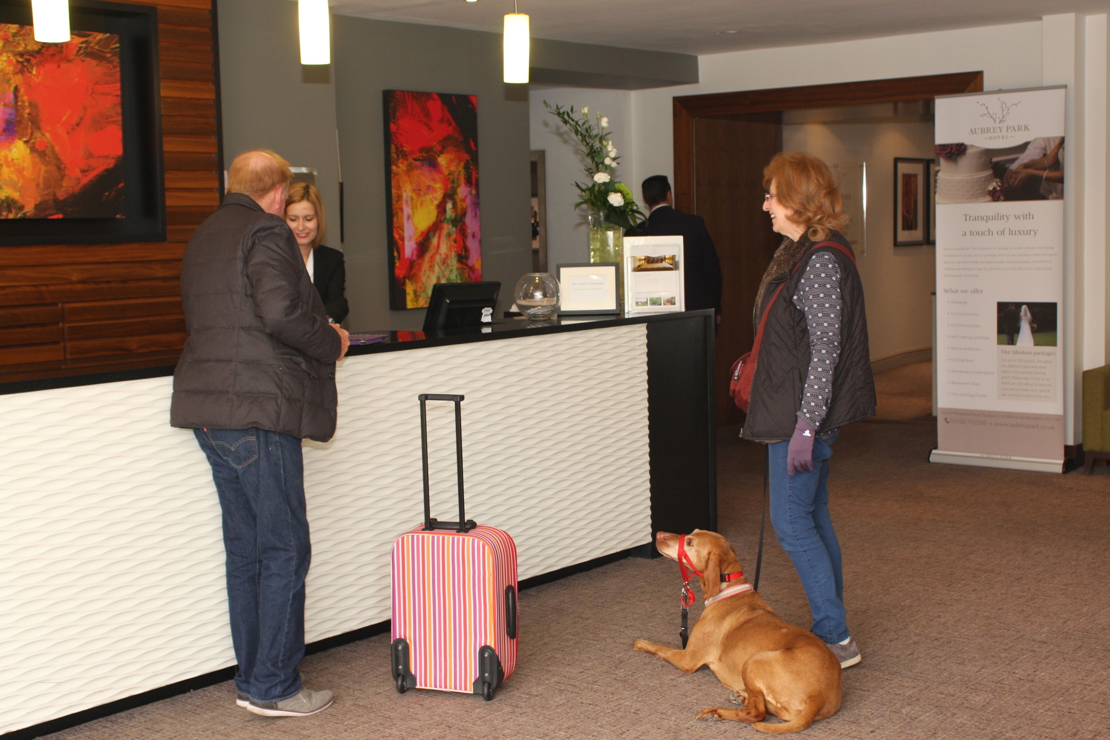 A reception desk with a modern design, a framed artwork on the wall, and a signboard with text.