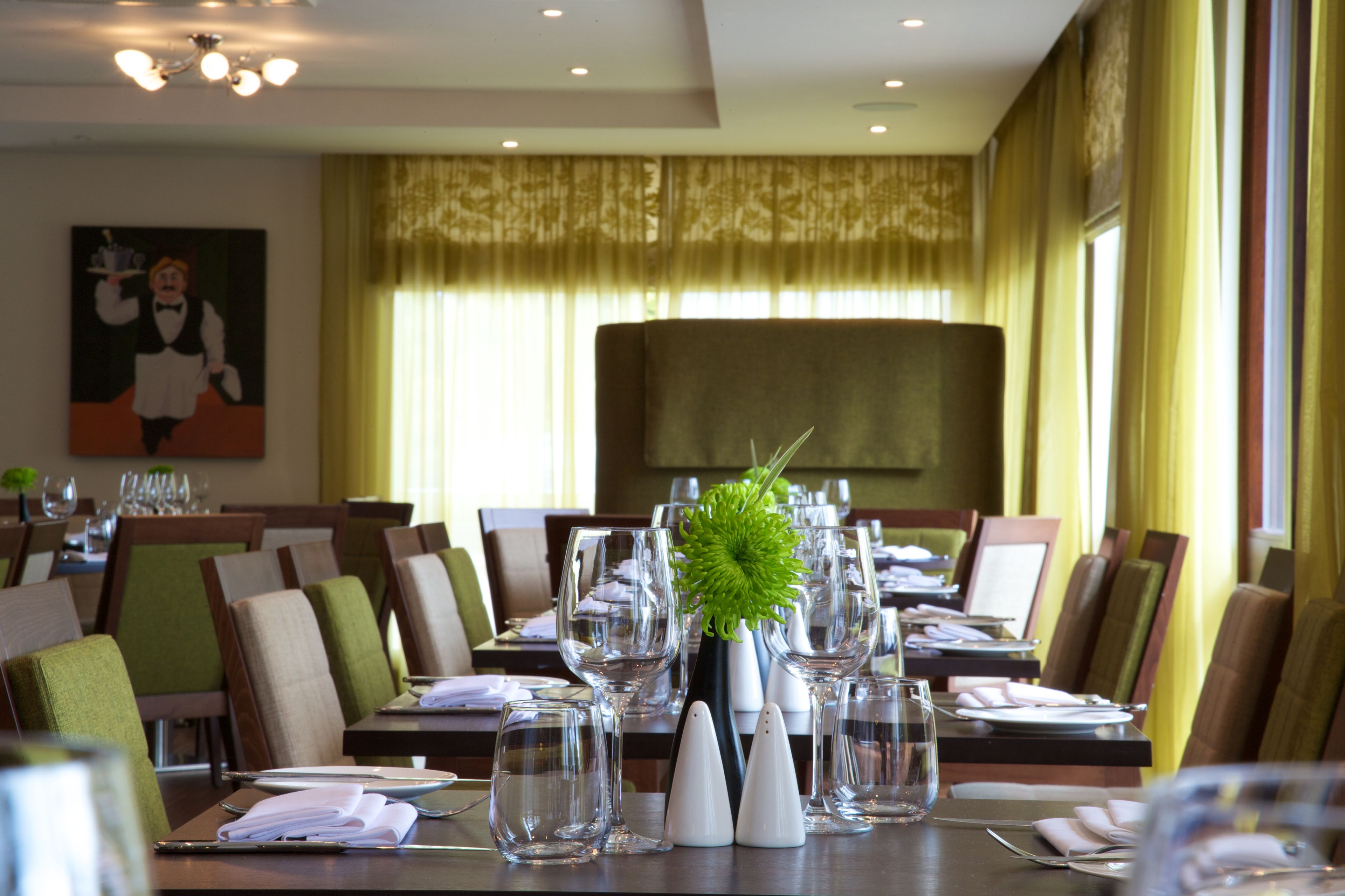 A dining area with tables set for a meal, including wine glasses, plates, and cutlery.