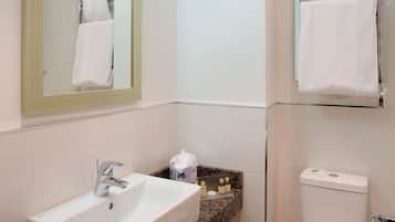 Un baño con lavabo, espejo, inodoro y toallero.