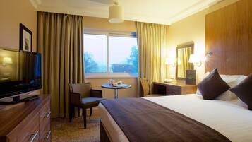 A hotel room with a bed, a TV, a desk, and a chair.