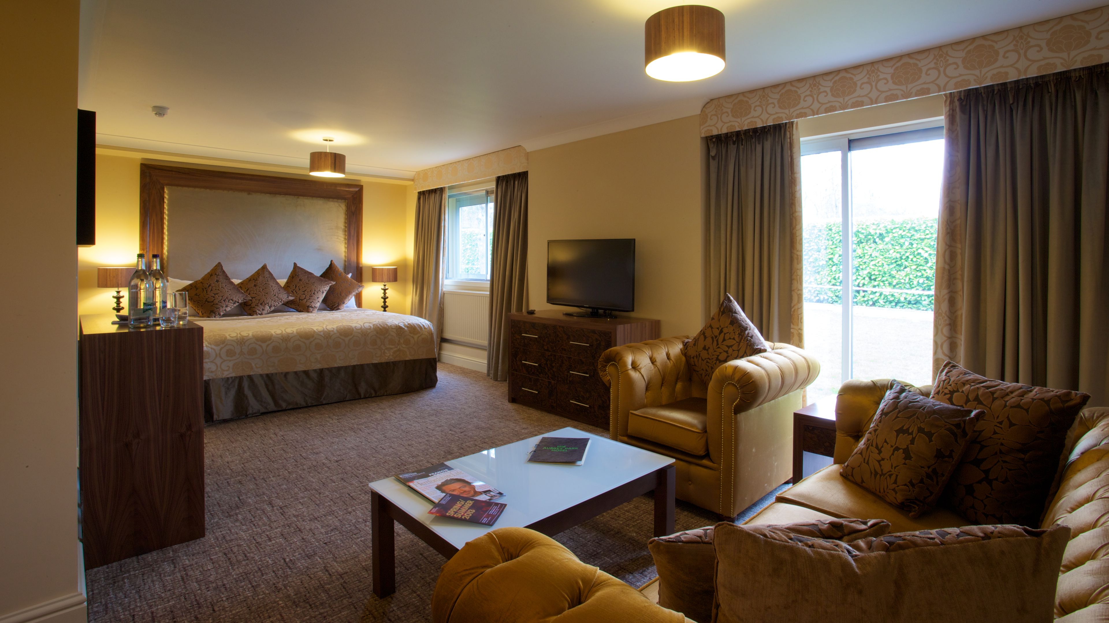 A hotel room with a bed, a sofa, a coffee table, a TV, and a dresser.