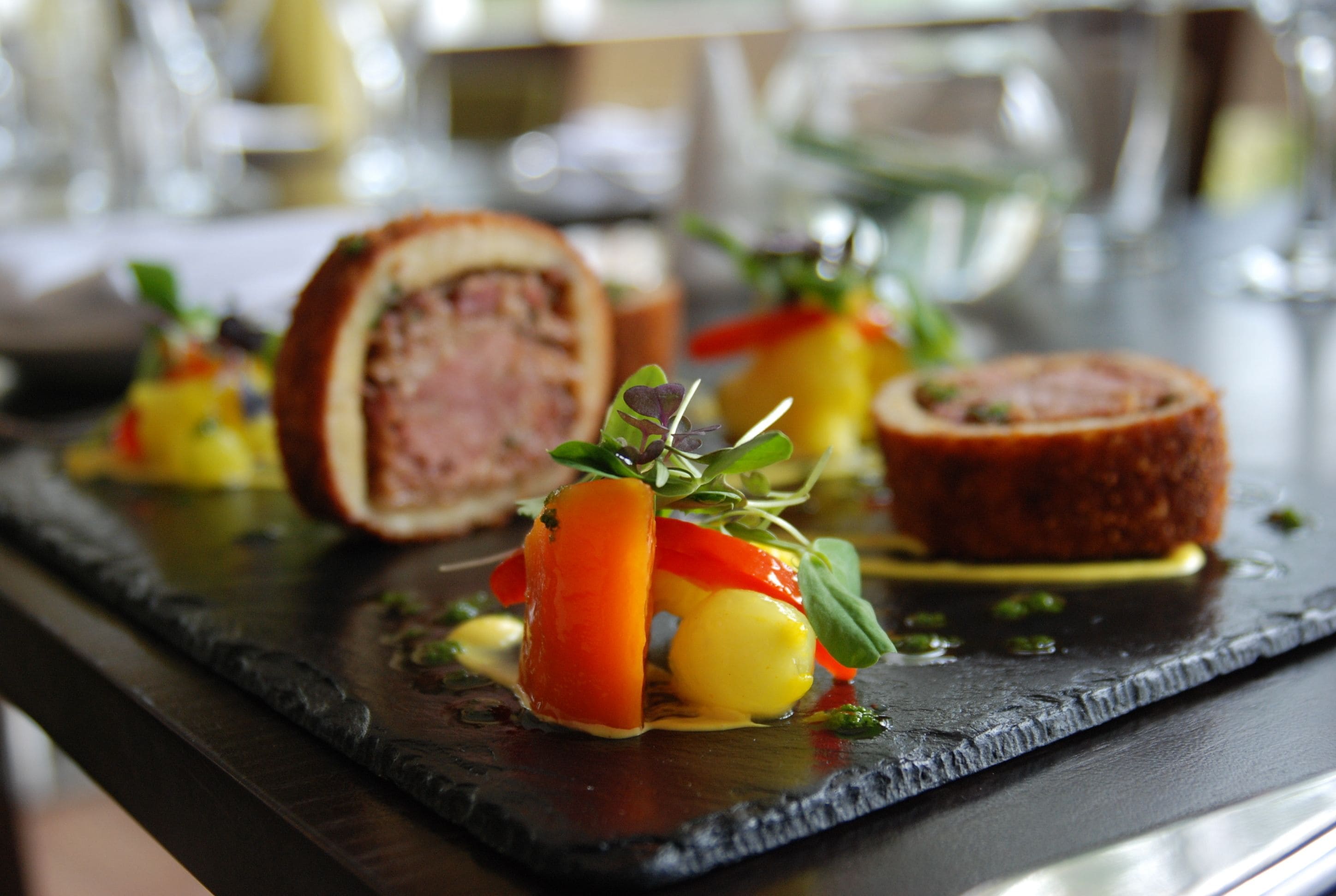 A dining table with a variety of dishes, including a rolled meat dish and vegetables.