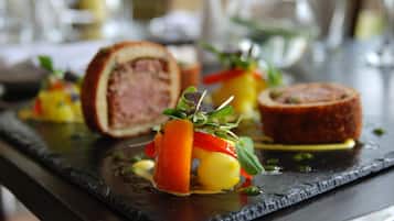 A dining table with a variety of dishes, including a rolled meat dish and vegetables.