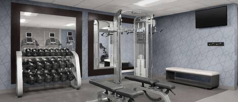 Un gimnasio moderno con equipo de levantamiento de pesas, mancuernas y una banca.