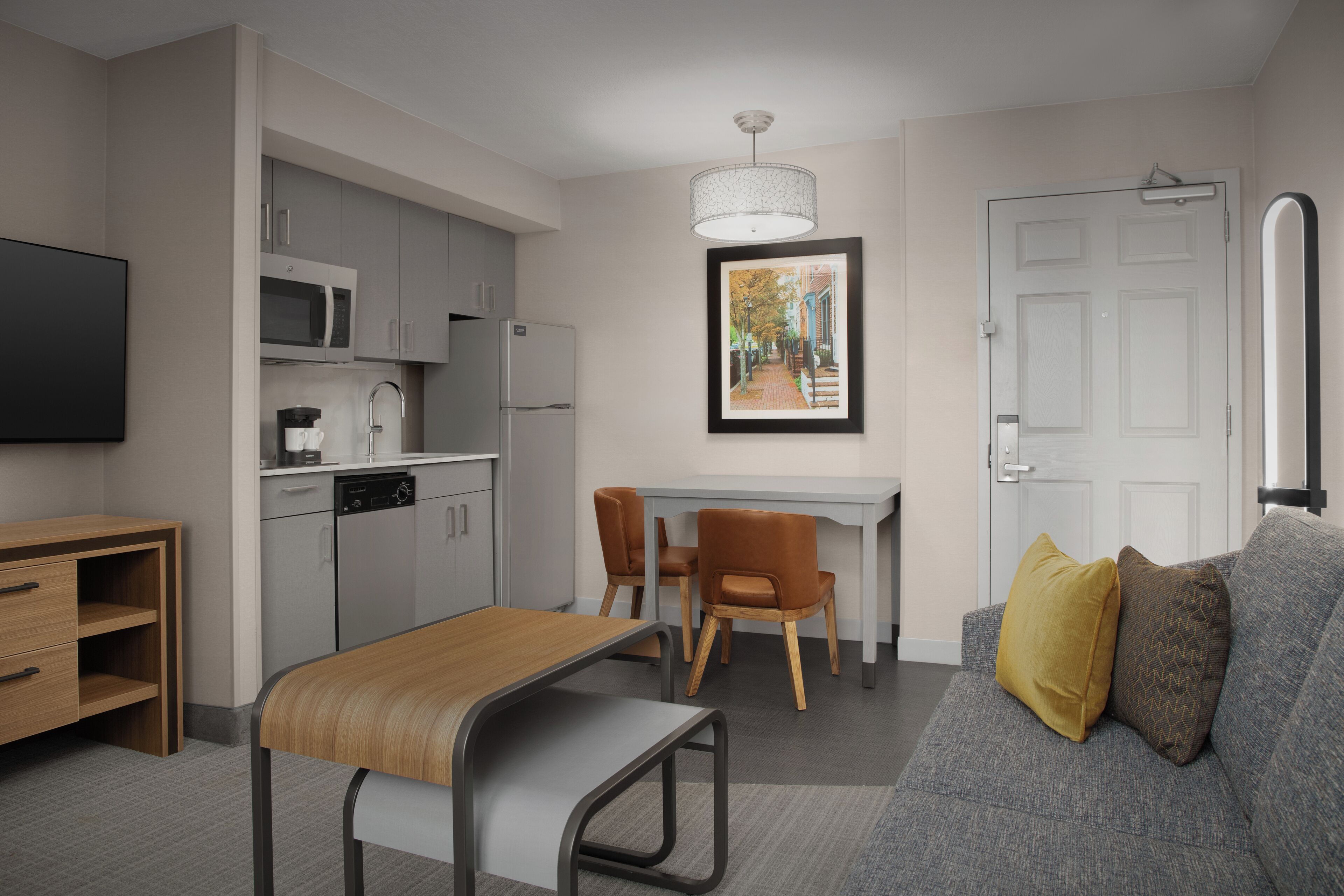A modern kitchen with a dining area, a sofa, and a TV.