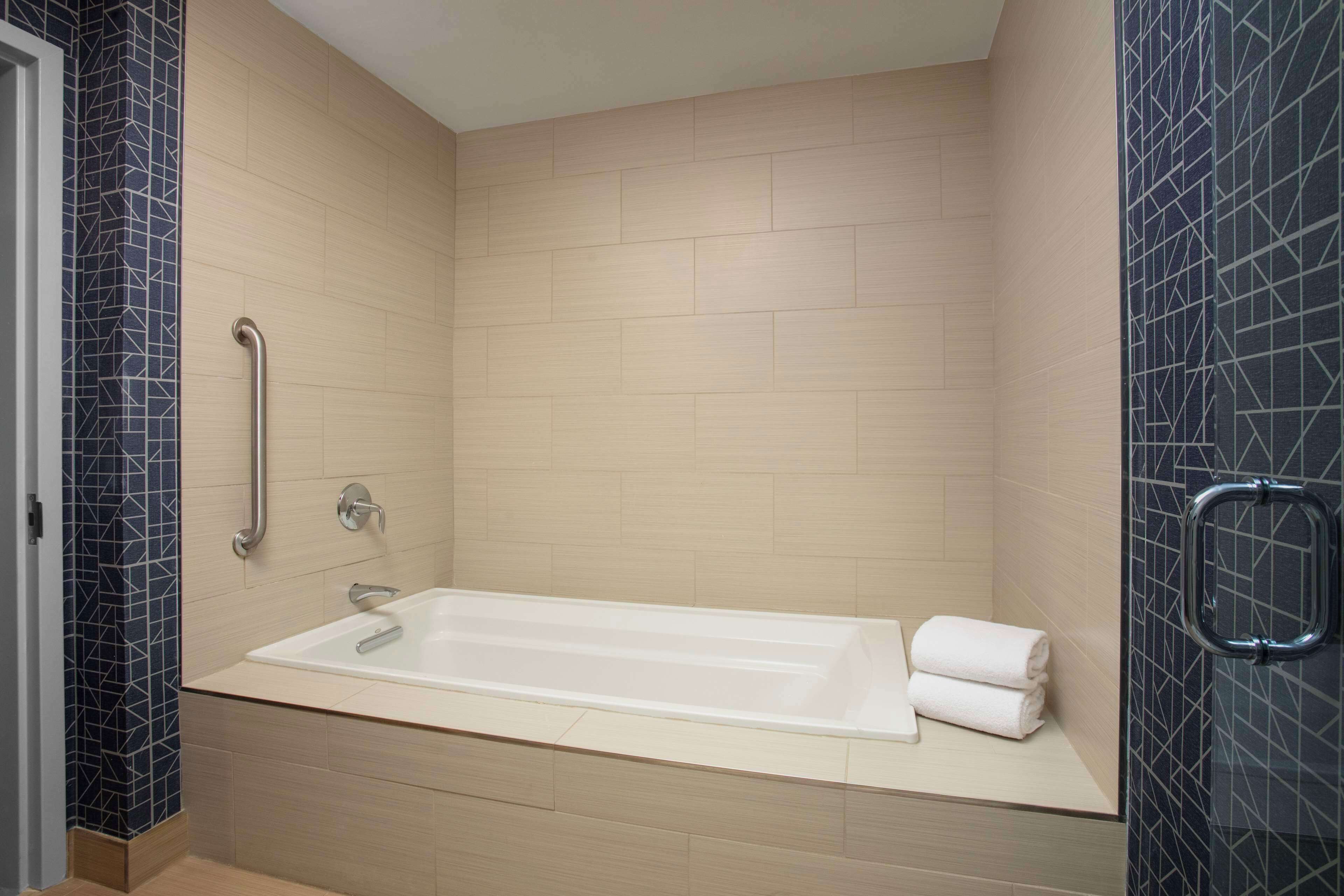 Ein modernes Badezimmer mit Badewanne, Handläufe und Handtuchhalter.