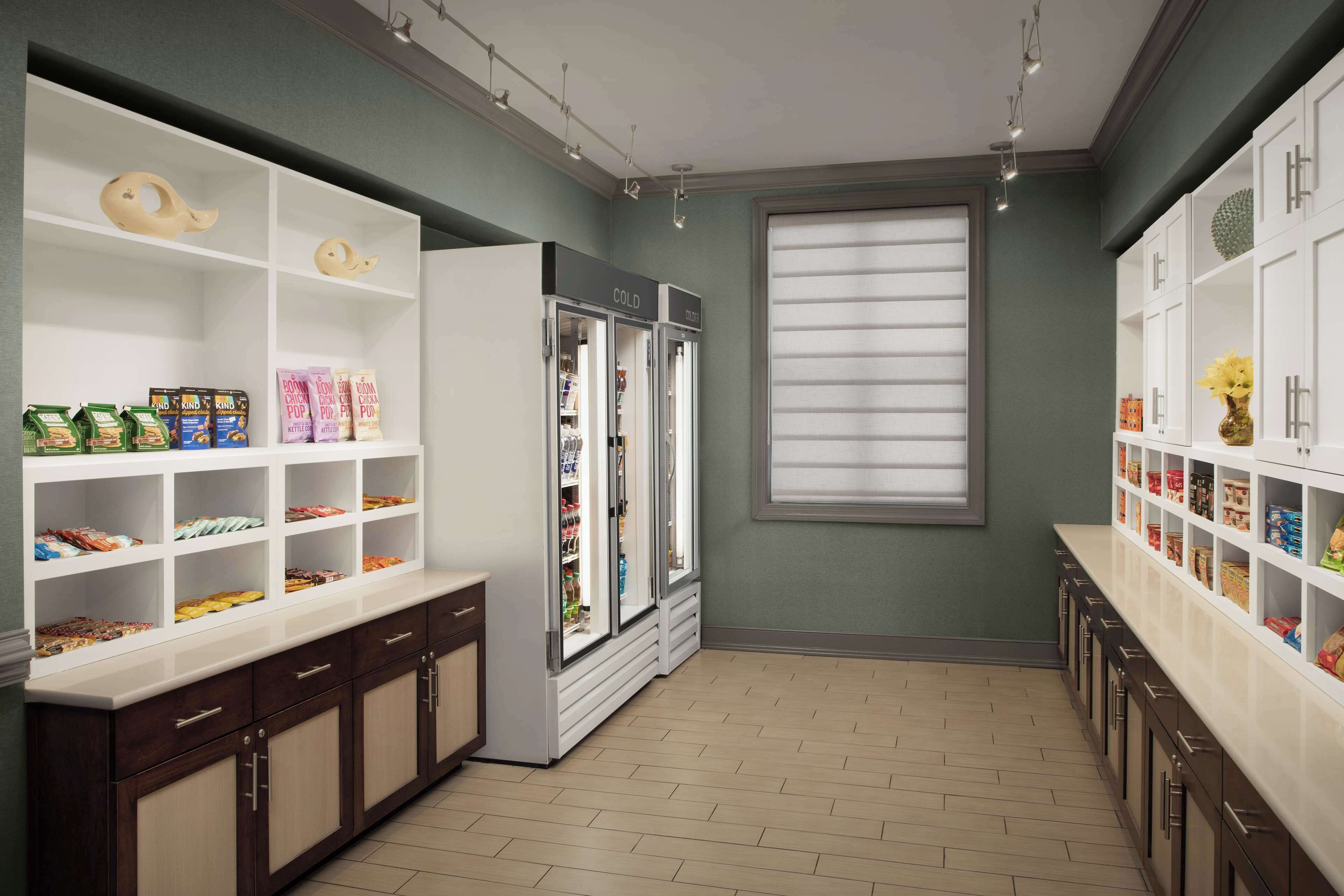 Una cocina con armarios blancos, un refrigerador y una ventana con persianas.