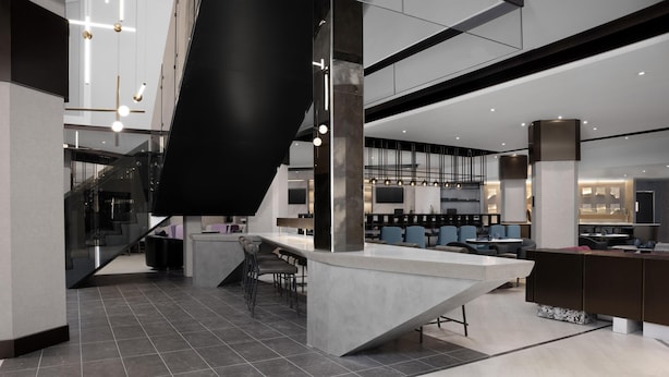 A modern interior with a central island, seating area, and a staircase.