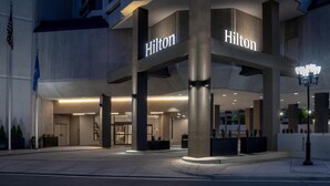A modern hotel entrance with 'Hilton' signage, large pillars, and a well-lit facade.