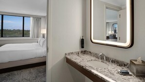 A hotel room with a bed, a bathroom with a marble sink, and a large mirror.