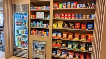 En försäljningsautomat fylld med snacks och drycker, inklusive märken som Lay’s, Doritos och Cheetos, placerad i en väl upplyst inomhusmiljö.