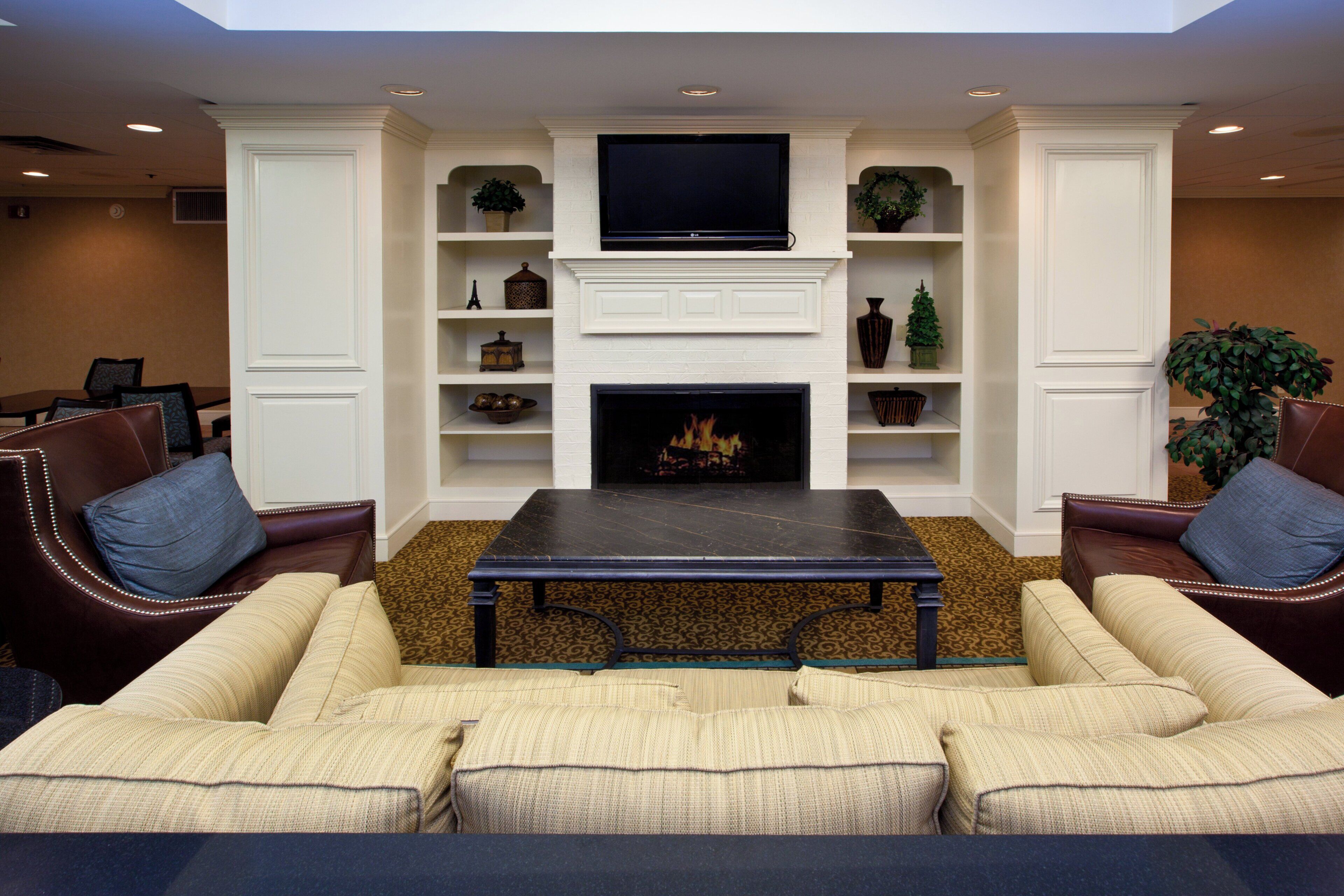A living room with a fireplace, a flat-screen TV, and a patterned carpet.