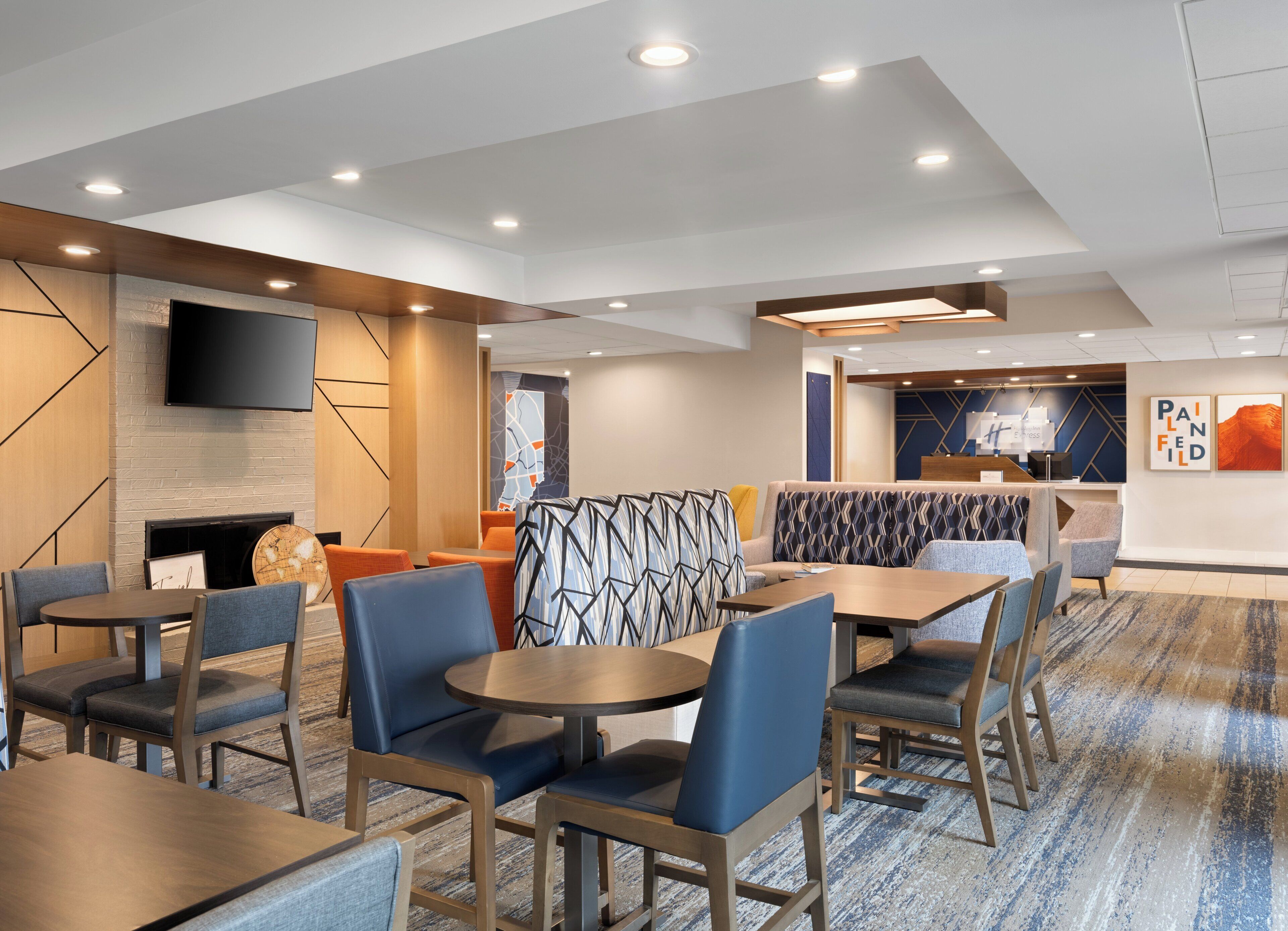 Un hall d’hôtel moderne, doté d’espaces aménagés avec des sièges, d’une cheminée et d’un comptoir de réception.