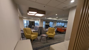 Um hall de hotel moderno com poltronas amarelas, um sofá e uma mesa de centro.