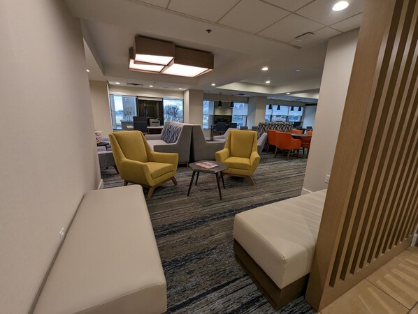 A modern hotel lobby with yellow armchairs, a sofa, and a coffee table. - Holiday Inn Express Indianapolis Airport by IHG (Plainfield)
