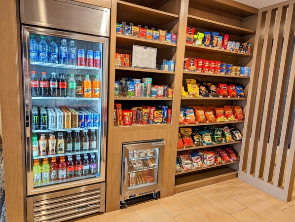 Máquina expendedora de bebidas con diversas opciones y estante de snacks con varias marcas.