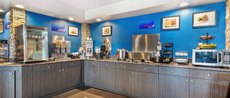 A modern kitchen with granite countertops, stainless steel appliances, and blue walls.