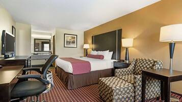 A hotel room with a bed, desk, chair, and a TV.