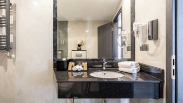 A modern bathroom with a black granite countertop, a white sink, a towel rack, and a mirror.