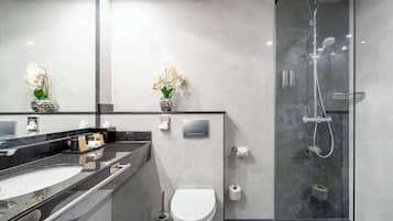 A modern bathroom with a glass-enclosed shower, a white toilet, and a black countertop with a sink.