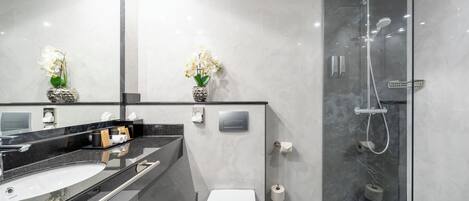 A modern bathroom with a glass-enclosed shower, a white toilet, and a black countertop with a sink.