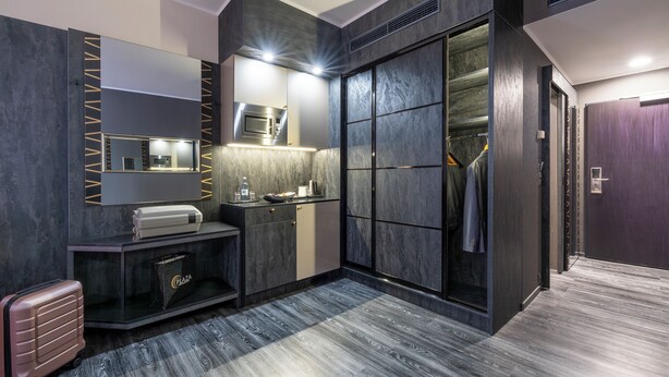 Une salle de bain moderne dotée d’un grand miroir, d’un four à micro-ondes encastré et d’un meuble-lavabo avec un distributeur de serviettes.