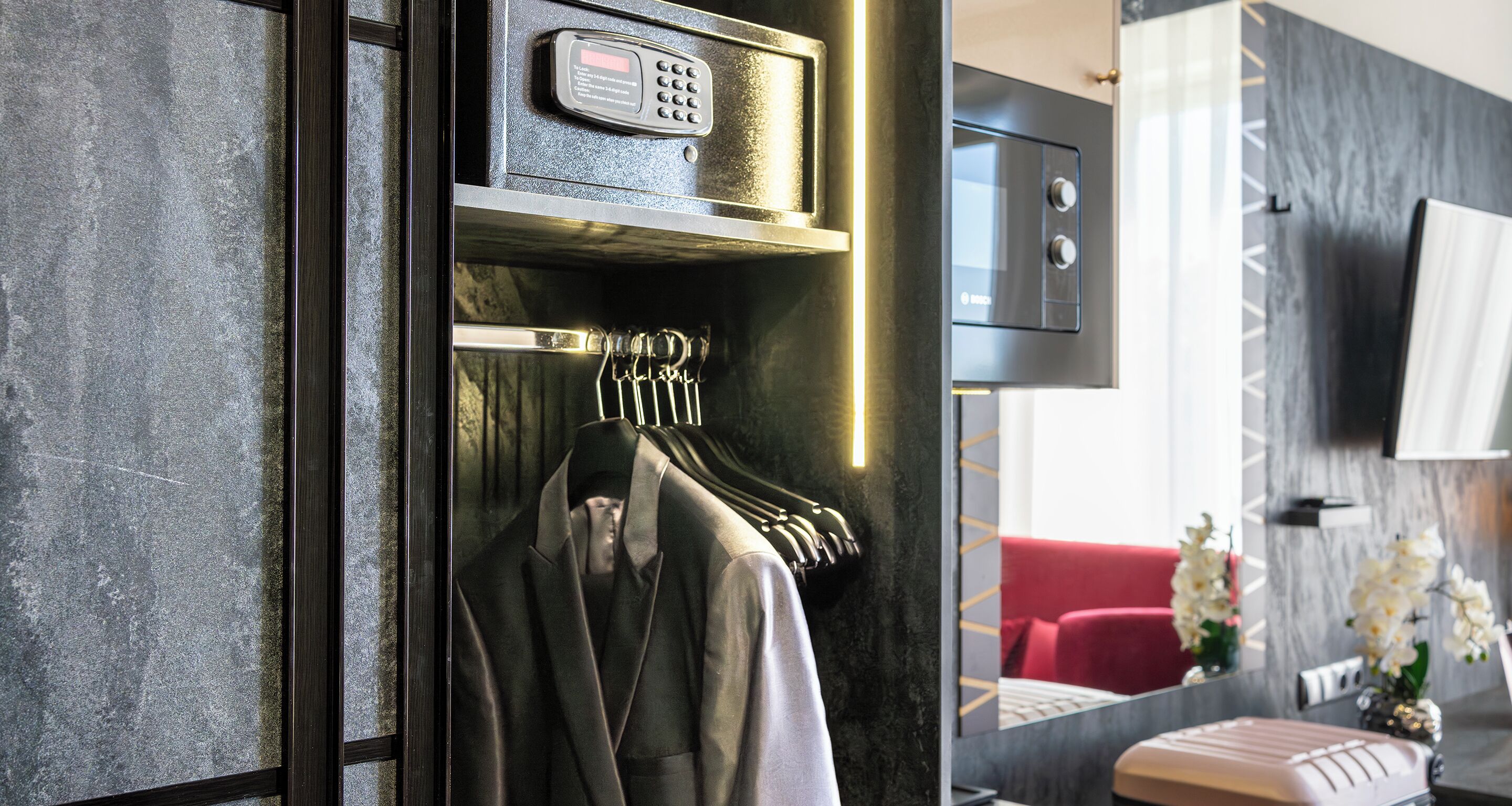 A modern hotel room with a coat rack, a minibar, and a television mounted on the wall.