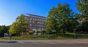 A multi-story hotel with a prominent 'Plaza Schwerin' sign, surrounded by lush greenery and a clear blue sky. - PLAZA Premium Schwerin (Schwerin)