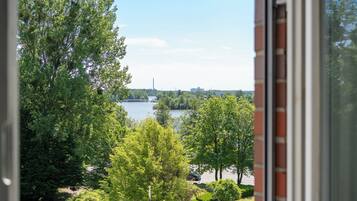 A view through a window of a lake surrounded by trees and a distant city skyline.