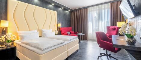 Una habitación de hotel moderna con una cama grande, un escritorio con una silla y un televisor montado en la pared.