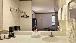 Casa de banho de hotel com lavatório, espelho, porta-toalhas e secador de cabelo.