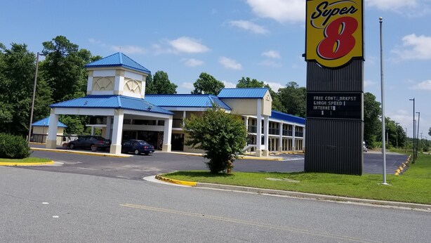 Um hotel Super 8 com um edifício de telhado azul, estacionamento e uma placa.