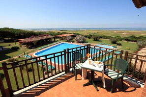 A balcony with a view of a swimming pool and a golf course.